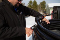 Contractor cutting zip ties to uncoil Heat-Line Freeze Protected Pipe System on Tailgate